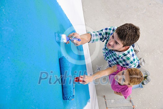 happy young couple paint in green and blue color white wall of their new home happy young couple paint in green and blue color white wall of their new home
