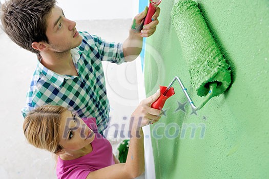 happy young couple paint in green and blue color white wall of their new home