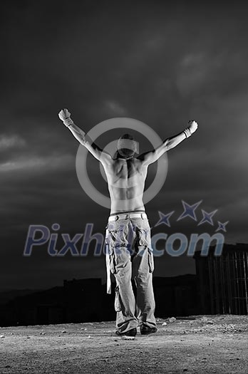 Man with his arms wide open outdoor against dark sky