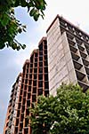 Building construction in city with blue sky in background and green trees in front