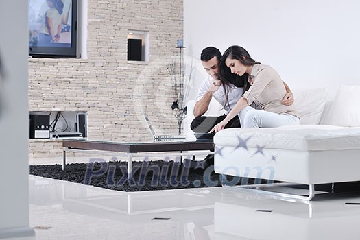 joyful couple relax and work on laptop computer at modern living room indoor home joyful couple relax and work on laptop computer at modern living room indoor home