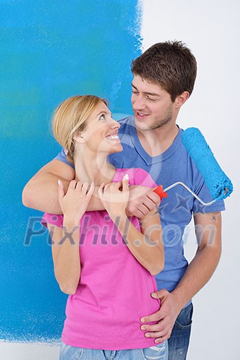 happy young couple paint in green and blue color white wall of their new home happy young couple paint in green and blue color white wall of their new home