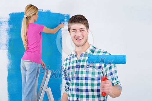 happy young couple paint in green and blue color white wall of their new home happy young couple paint in green and blue color white wall of their new home