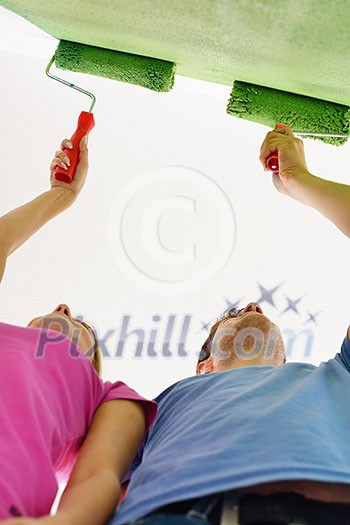 happy young couple paint in green and blue color white wall of their new home happy young couple paint in green and blue color white wall of their new home