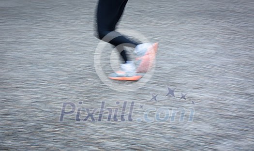 Motion blurred runner's feet in a city environment (panning technique used -> motion blurred image; color toned image)