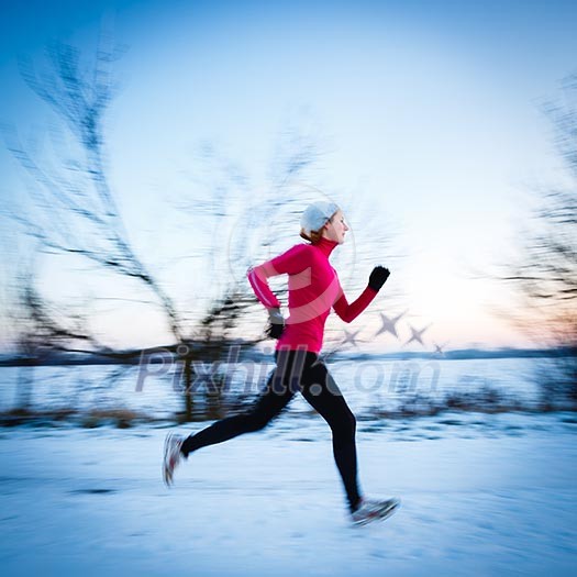 Winter running - Young woman running outdoors on a cold winter day (motion blurred image, color toned image)