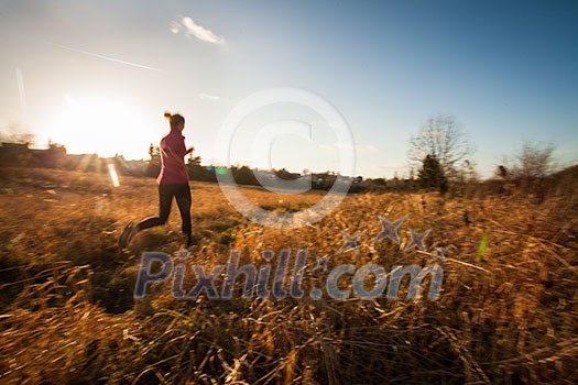 Young woman running outdoors on a lovely sunny winter/fall day (motion blurred image)