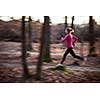 Young woman running outdoors in a city park on a cold fall/winter day (motion blurred image)