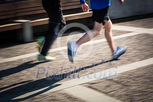 Motion blurred runner's feet in a city environment (panning technique used -> motion blurred image; color toned image)