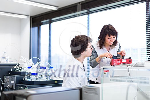 Two young researchers carrying out experiments in a lab (shallow DOF; color toned image) Two young researchers carrying out experiments in a lab (shallow DOF; color toned image)