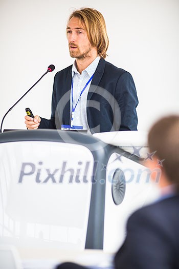 Handsome young man giving a speech at a conference Handsome young man giving a speech at a conference