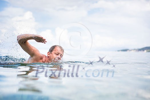 Senior man swimming in the Sea/Ocean - enjoying active retirement, having fun, taking care of himself, staying fit