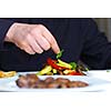 Handsome chef dressed in black uniform decorating tasty food in restaurant