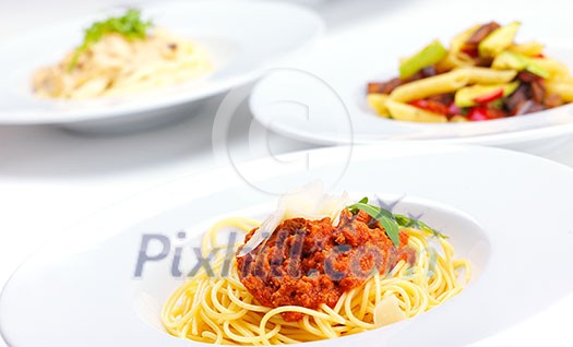 Italian spaghetti topped with bolognaise, or bolognese, sauce with tomatoes, meat and cheese on a plain white plate