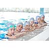 group of happy kids children   at swimming pool class  learning to swim