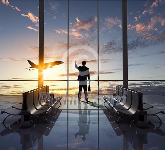 Businessman at airport looking at airplane taking off