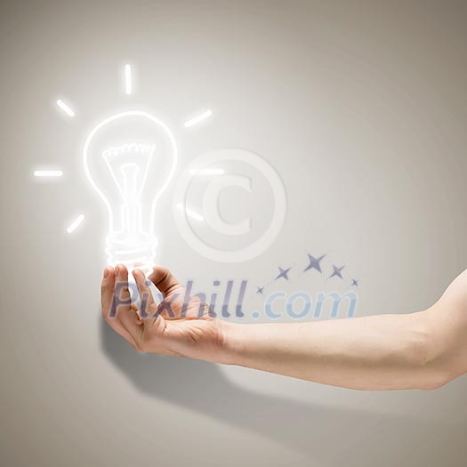 Close up image of human hand holding electrical bulb Close up image of human hand holding electrical bulb