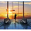 Image of woman in airport looking at taking off airplane