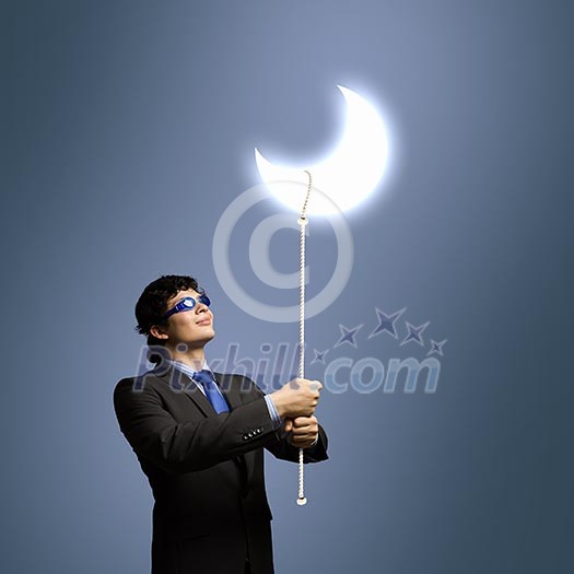 Image of young businessman in goggles looking at moon Image of young businessman in goggles looking at moon