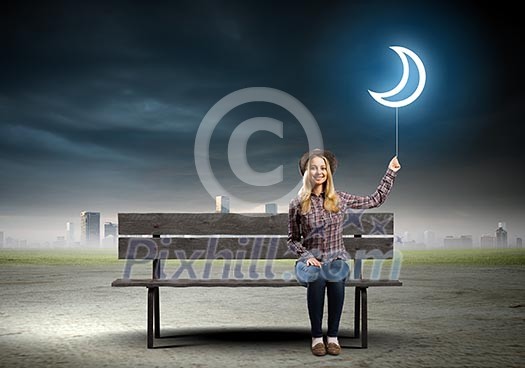 Young woman in casual sitting on bench and holding balloon