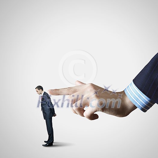Close up of male businessman pointing at miniature of man Close up of male businessman pointing at miniature of man