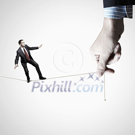 Young businessman balancing on rope controlled by male hand