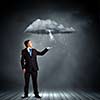 Young businessman under raining sky. Failure concept