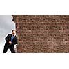 Young businessman making effort to move brick wall