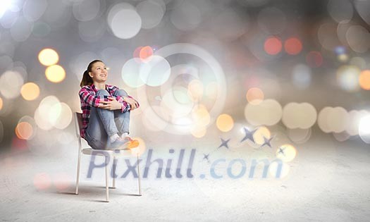 Young woman sitting on chair with bokeh lights at background