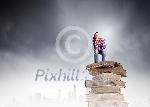 Young girl sitting on high pile of books