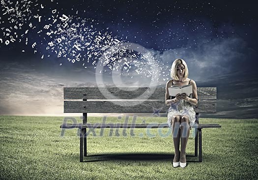 Young pretty woman sitting on bench and reading book Young pretty woman sitting on bench and reading book