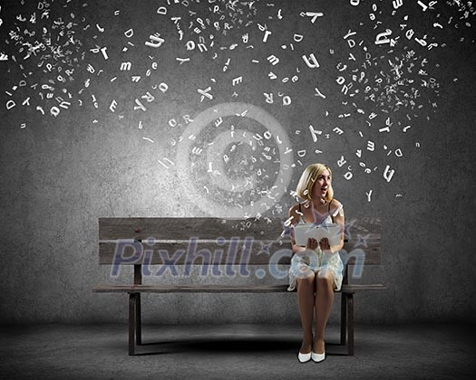 Young pretty woman sitting on bench and reading book Young pretty woman sitting on bench and reading book