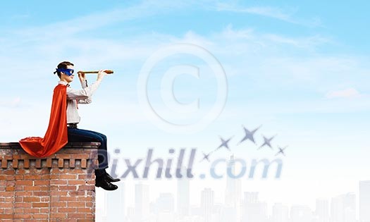 Superman in cape and mask sitting on top of building