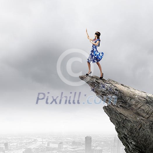 Young woman in blue dress standing on mountain edge Young woman in blue dress standing on mountain edge