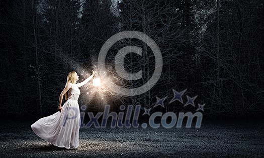 Young woman in white long dress walking in night wood Young woman in white long dress walking in night wood