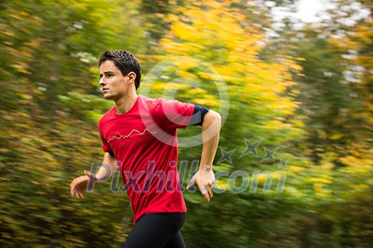 Young man running outdoors in a city park on a fall/autumn day (motion blurred image)