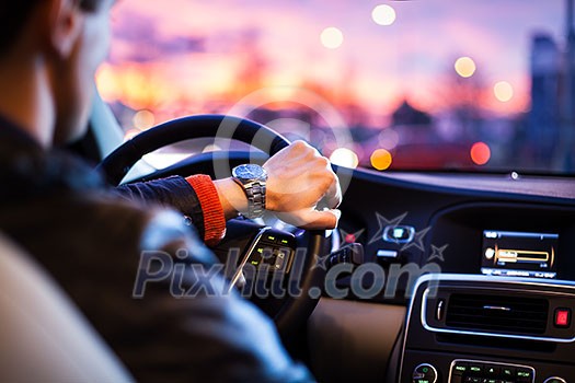 Driving a car at night -man driving his modern car at night in a city (shallow DOF; color toned image)