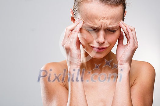 Beautiful woman suffering from acute headache over grey clean background