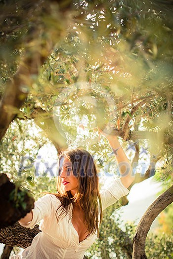 Attractive, young brunette on the beach, amid olive trees, looking both sensual and natural