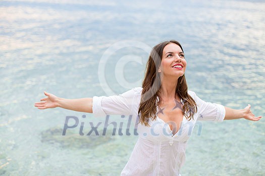Woman relaxing at the beach with arms open enjoying her freedom, independence, good health, time off. Woman relaxing at the beach with arms open enjoying her freedom, independence, good health, time off.