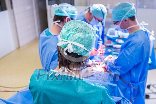 Team of surgeons performing an operation on a patient in a hospital (shallow DOF; color toned image)