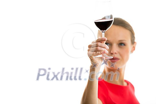 Elegant young woman in a red dress, having a glass of red wine isolated on white background