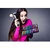 Cute make-up artist holding her vast palette of colors and hands with brushes around her (color toned image)