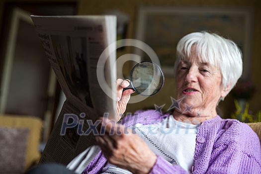 Senior woman reading morning newspaper, sitting in her favorite chair in her living room, looking happy