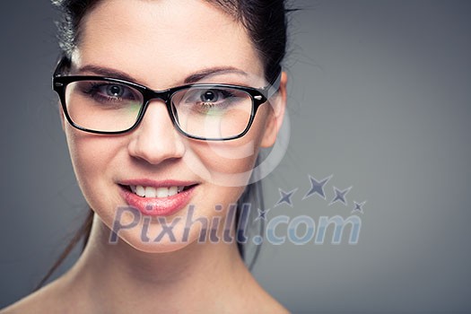 Portrait of a smiling pretty, young woman wearing glasses with copy space - studio shot, color toned