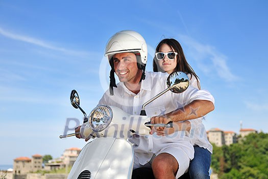 Portrait of happy young love couple on scooter enjoying themselves in a park at summer time Portrait of happy young love couple on scooter enjoying themselves in a park at summer time