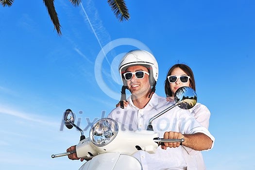 Portrait of happy young love couple on scooter enjoying themselves in a park at summer time