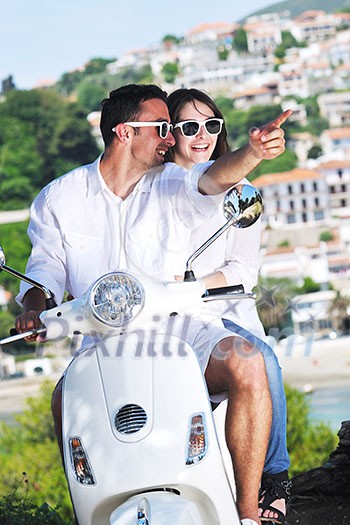 Portrait of happy young love couple on scooter enjoying themselves in a park at summer time Portrait of happy young love couple on scooter enjoying themselves in a park at summer time