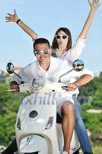 Portrait of happy young love couple on scooter enjoying themselves in a park at summer time Portrait of happy young love couple on scooter enjoying themselves in a park at summer time