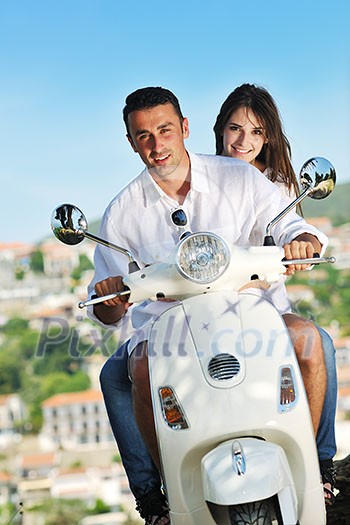 Portrait of happy young love couple on scooter enjoying themselves in a park at summer time